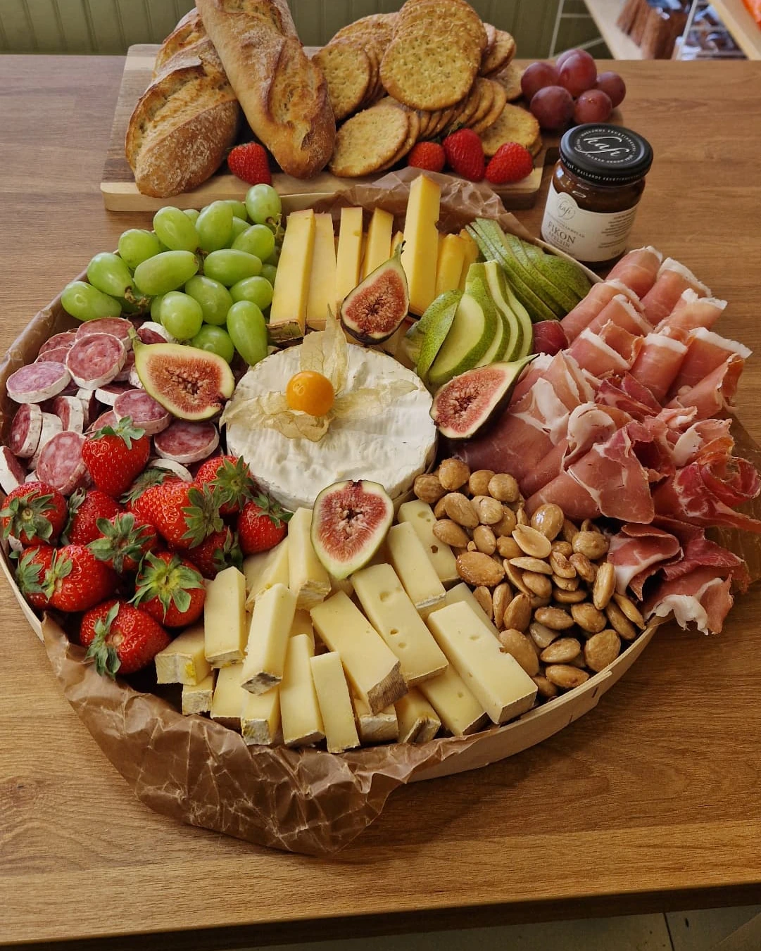 Stor grazingbricka med ost, chark, frukt och bröd på bordet i butiken