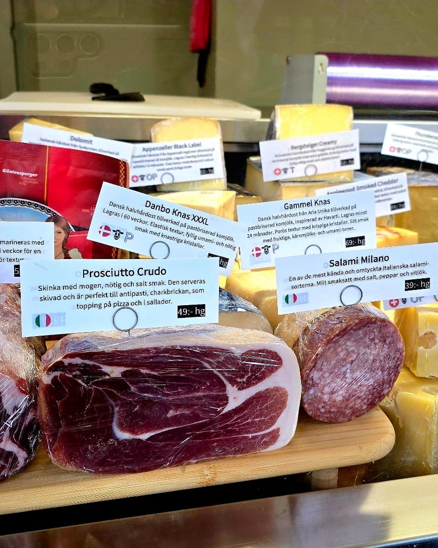 Charkdisken med prosciutto, coppa och salami framför hyllan med hårdostar