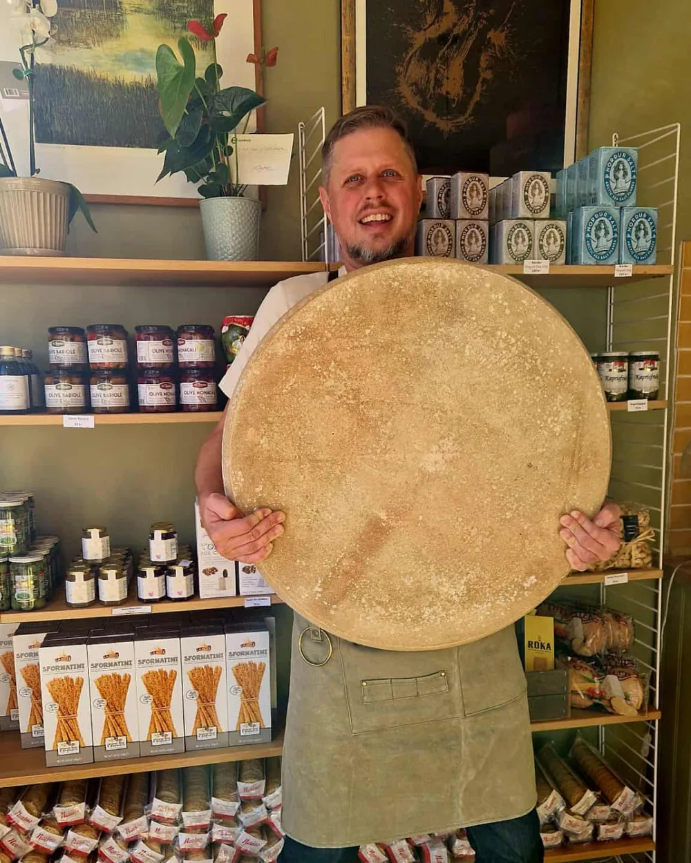 Andreas Holm håller ett stort osthjul i Brie & Bekantas butik